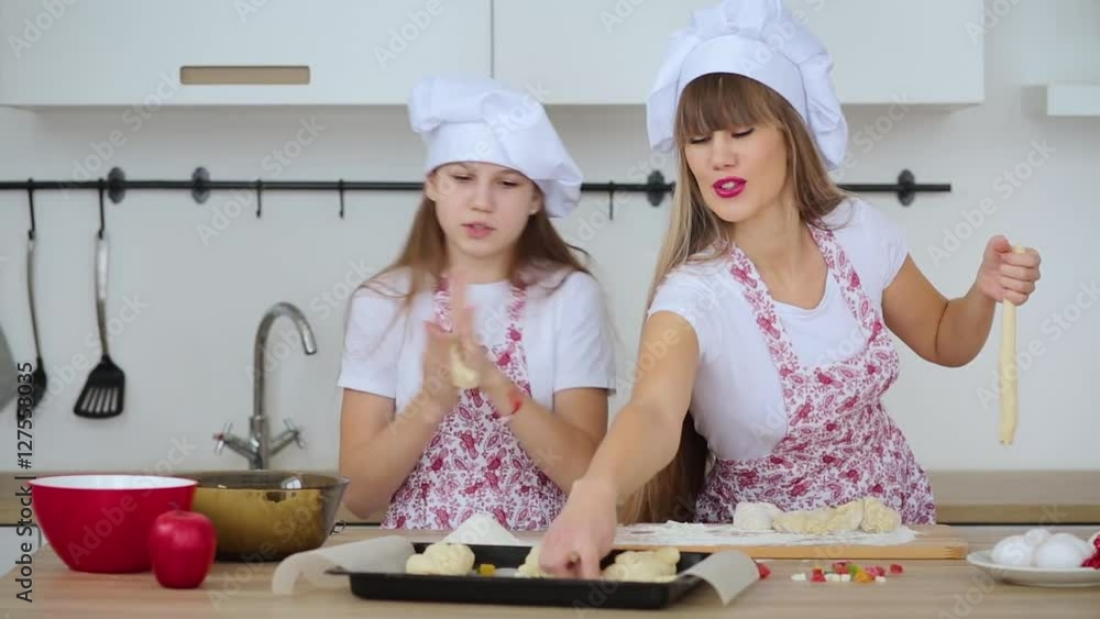 Mother and daughter in hats and aprons to cook scones for Christmas Mother and daughter in hats and aprons to cook scones for Christmas