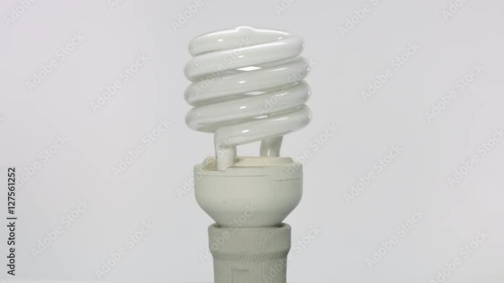 Rotating vertical spiral fluorescent light bulb in holder on white background Rotating vertical spiral fluorescent light bulb in holder on white background