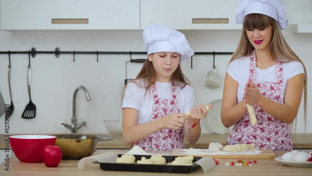 Mother and daughter in hats and aprons to cook scones for Christmas Mother and daughter in hats and aprons to cook scones for Christmas