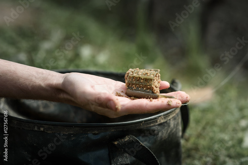 Bild auf Leinwand fishing feeder in hand against the bucket for bait
