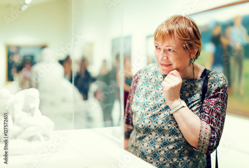 Portrait of retiree woman attentively looking at sculptures