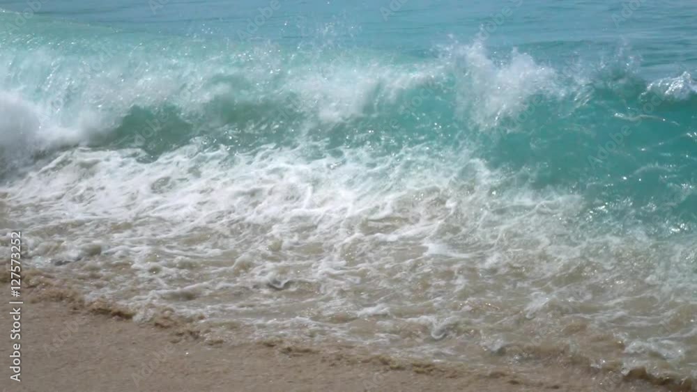 Slow motion, 240fps, of green sea wave with vibrant splash on brown sand beach. Beautiful natural background for amazing intro in excellent eight times decelerated clip.