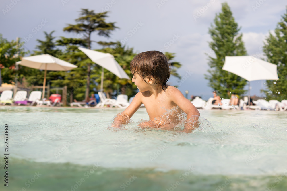 Young boy kid child splashing in swimming pool having fun leisur Young boy kid child splashing in swimming pool having fun leisur