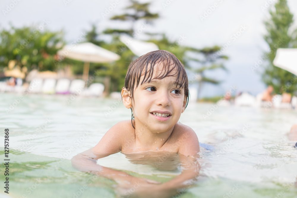 Young boy kid child splashing in swimming pool having fun leisur Young boy kid child splashing in swimming pool having fun leisur