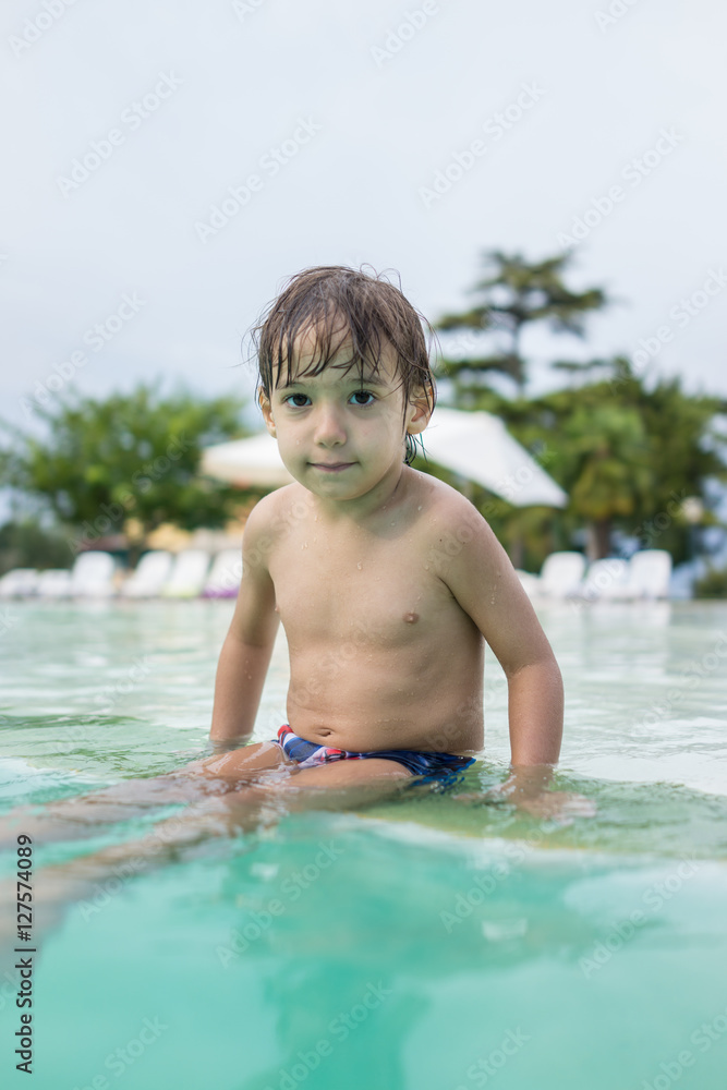 Young boy kid child splashing in swimming pool having fun leisur