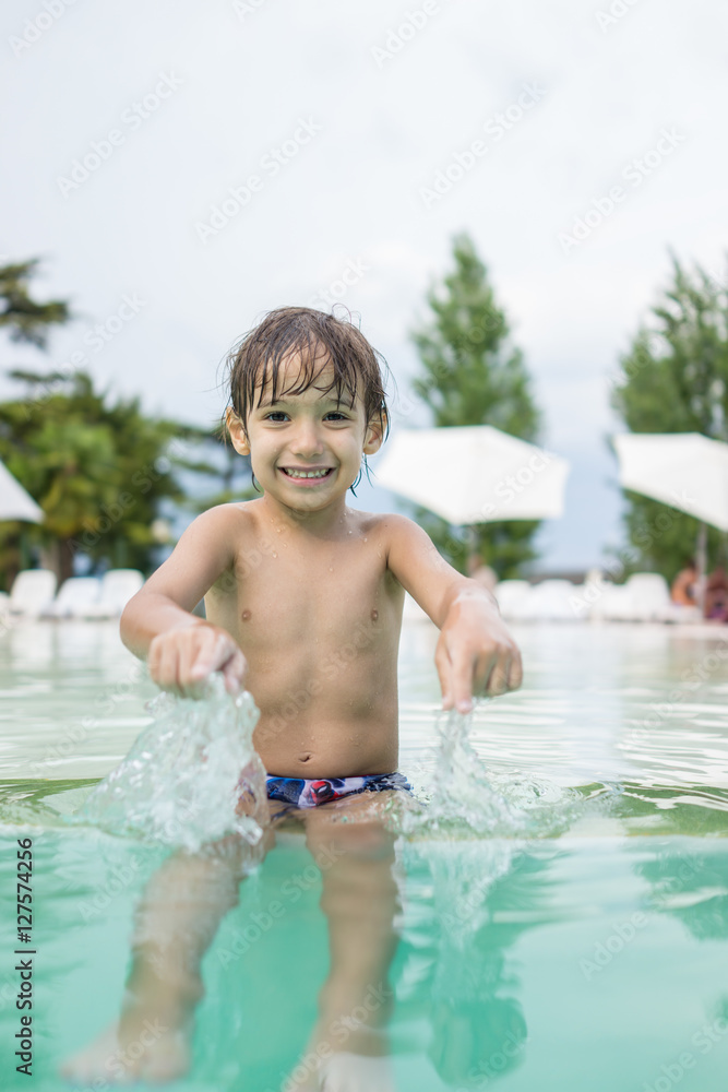 Young boy kid child splashing in swimming pool having fun leisur Young boy kid child splashing in swimming pool having fun leisur