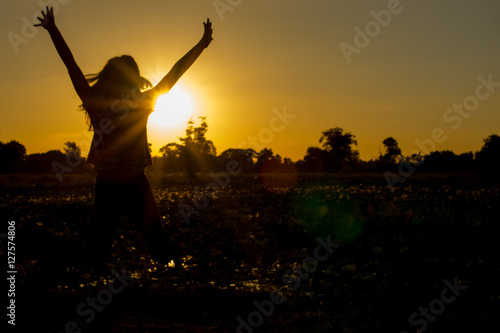 .Woman stands at sunset happily.