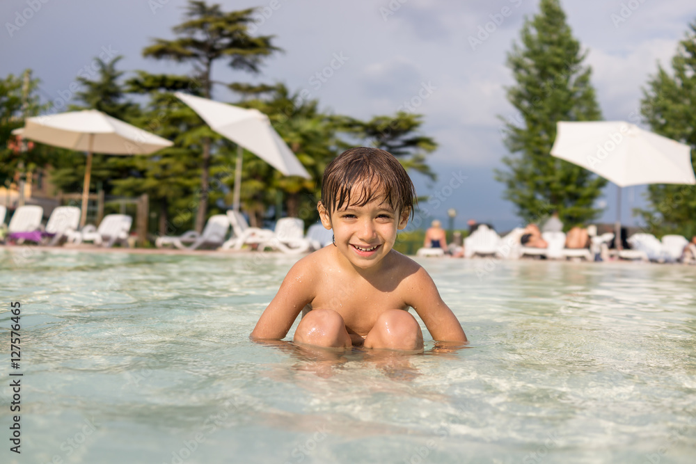 Young boy kid child splashing in swimming pool having fun leisur