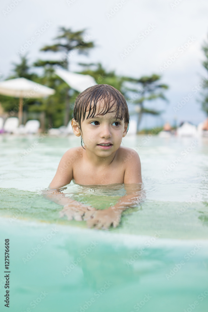 Young boy kid child splashing in swimming pool having fun leisur Young boy kid child splashing in swimming pool having fun leisur
