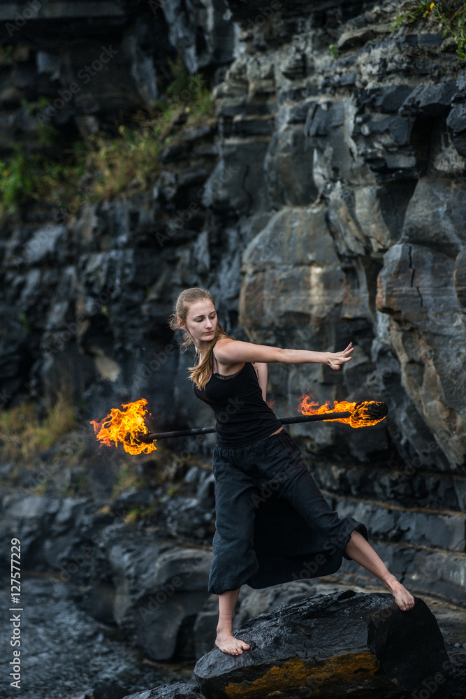 Obraz premium Girl in a black suit with flaming torches .