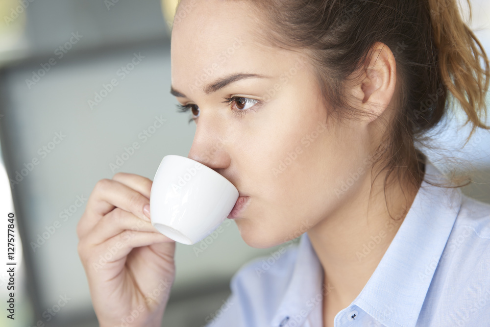 Starting working day with coffee. Close-up shot of a young businesswoman sitting at office and drinking coffee early morning. Starting working day with coffee. Close-up shot of a young businesswoman sitting at office and drinking coffee early morning.