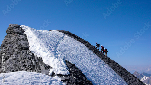 mountain guide and clients on a high alpine summit in the Swiss Alps photo