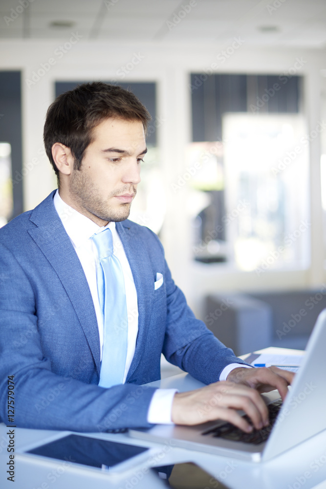 Young professional businessman with laptop. Shot of a young financial manager sitting in his workplace and working online. 