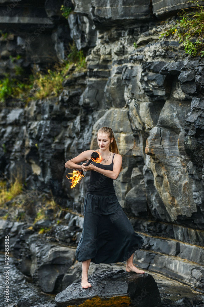 Girl in a black suit with flaming torches . Girl in a black suit with flaming torches .