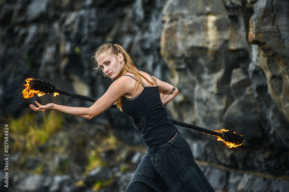 Girl in a black suit with flaming torches .