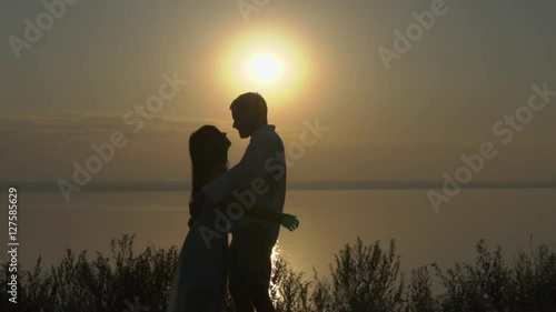 Happy young couple hugging and kissing near the sea on the sunset. Concept of love and relationships slow motion.