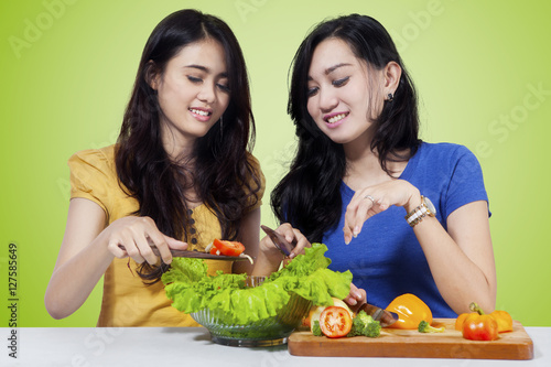 Two woman cooks vegetables salad