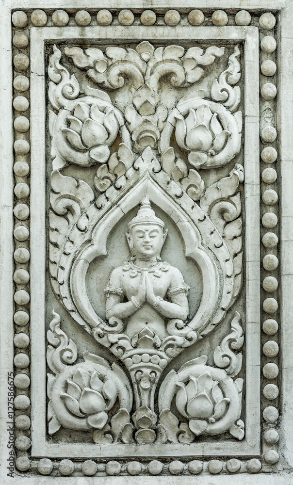 Ancient relief sculpture of deva in Buddhism with lotus flowers. The modeling is visual Buddhist religion arts made of concrete on Thailand temple wall.