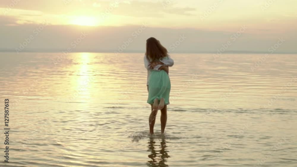 Young happy man pick up and whirl his girlfriend on the beach on the sunset. Concept of love and relationships slow motion. Young happy man pick up and whirl his girlfriend on the beach on the sunset. Concept of love and relationships slow motion.
