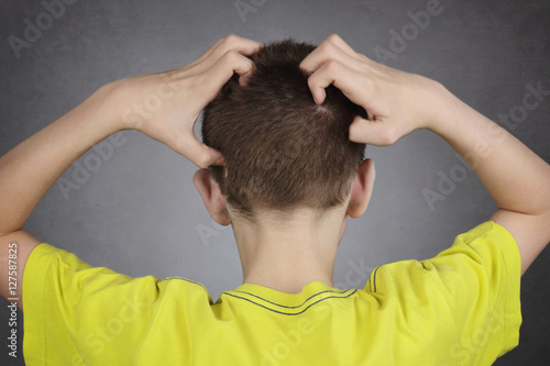 enfant garçon 14 ans se grattant la tête photo