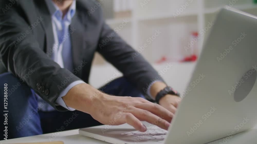 The young businessman sits at a table and works on his laptop The young businessman sits at a table and works on his laptop