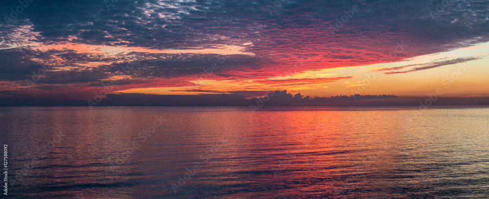 Panoramic view of beautiful sunset with scarlet clouds above the gulf.