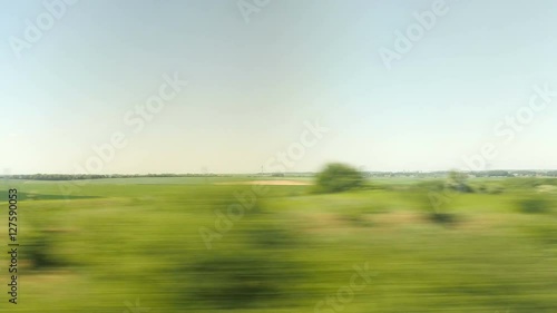 Green and yellow pastures passing by through train window in France.