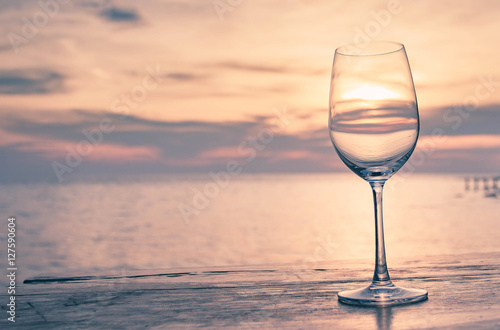 Glass of wine on a wooden table seaside sunset style sweet tone. The concept Romantic Dinner.Sea glass of wine.Background blurred ocean