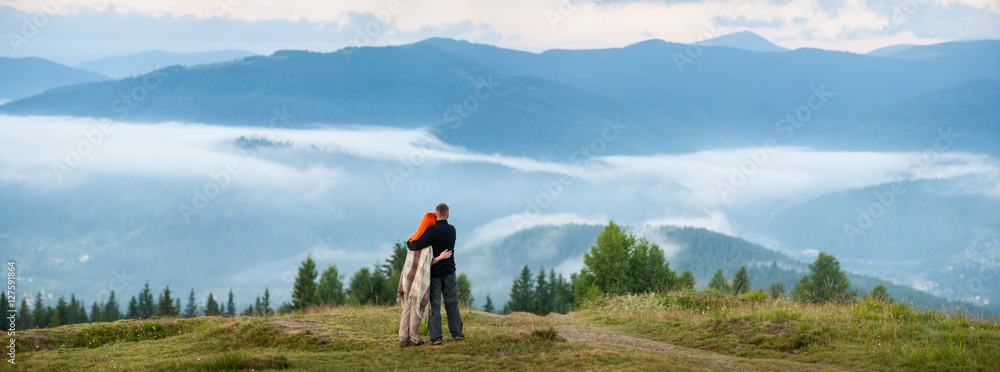 Tourist family - man and woman standing on a hill enjoying a morning ...