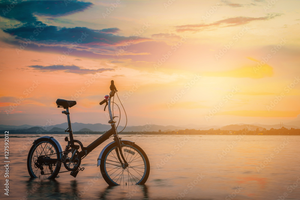 Silhouette bicycle on the beach at sunset. Vintage tone