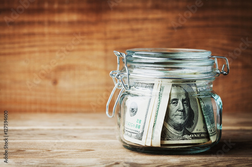 Принти на полотні Dollar bills in glass jar on rustic table. Saving money concept.