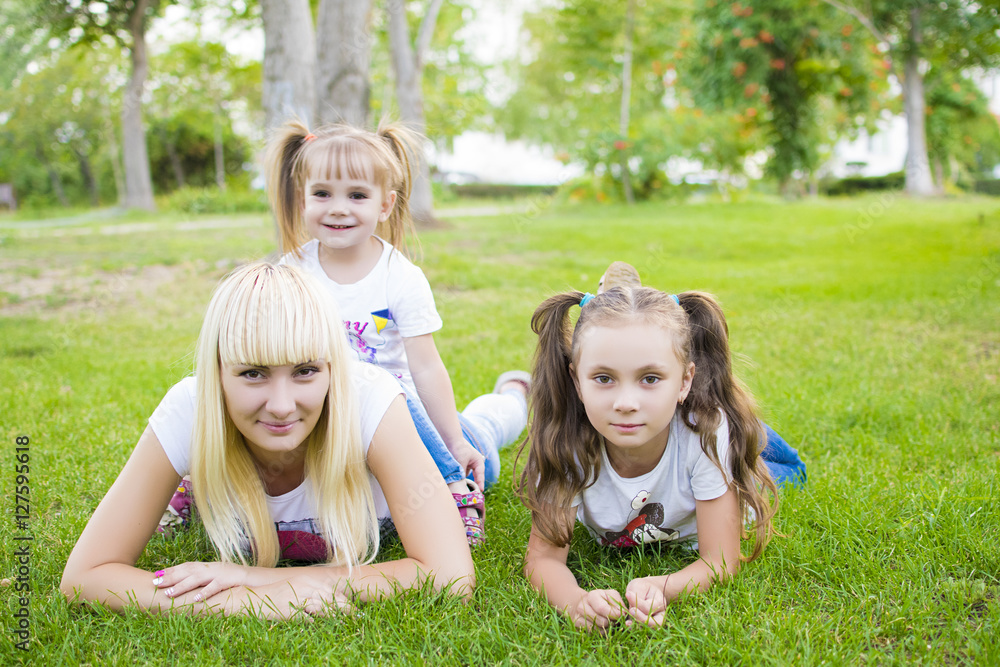 Young mother and two daughters playing in grass Young mother and two daughters playing in grass