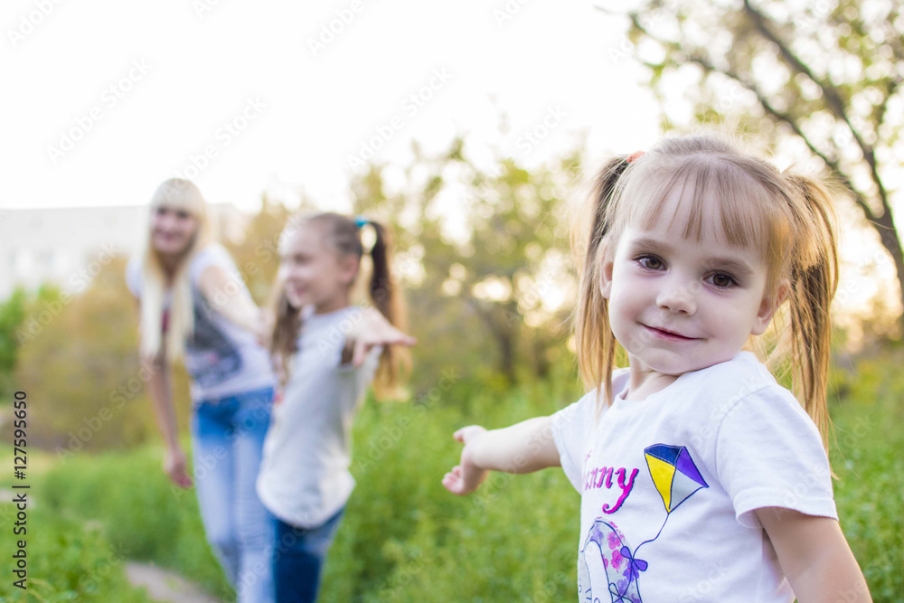Young mother and two daughters playing in grass Young mother and two daughters playing in grass