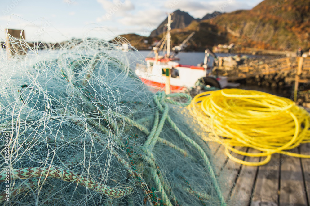 Many fishing nets and floats, stacked on a wooden dock. Fisheries, fishing. Fishing industry. In the distance is a fishing ship, boat. Background.