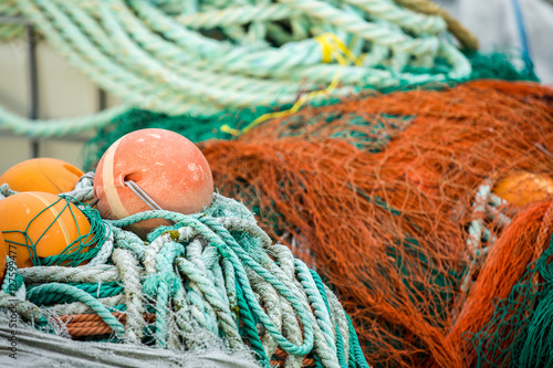 Many fishing nets and floats, stacked on a wooden dock. Fisheries, fishing. Fishing industry. In the distance is a fishing ship, boat. Background. photo