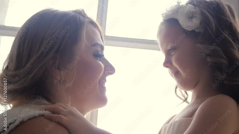 mother and daughter three years sitting by the large window in white dresses before the new year mother and daughter three years sitting by the large window in white dresses before the new year