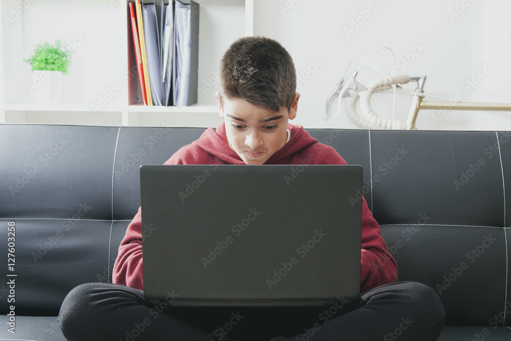 child with computer laptop sitting in the sofa of house child with computer laptop sitting in the sofa of house