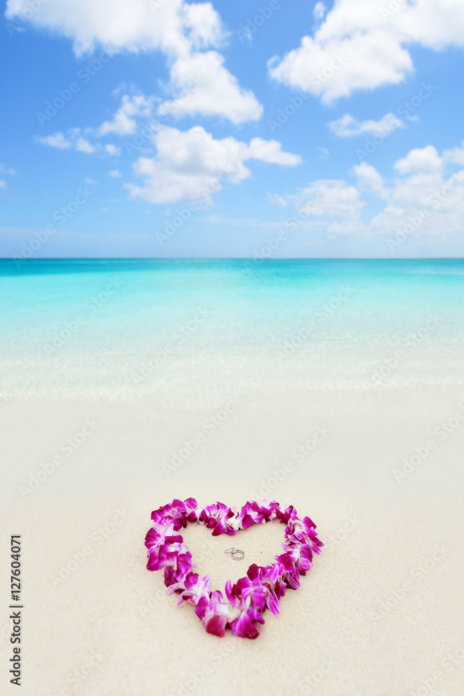Two wedding rings in a heart lei on beach vacation. Hawaiian flower necklace lying on the sand in the shape of a heart with rings for marriage proposal in tropical vacation destination honeymoon. Two wedding rings in a heart lei on beach vacation. Hawaiian flower necklace lying on the sand in the shape of a heart with rings for marriage proposal in tropical vacation destination honeymoon.