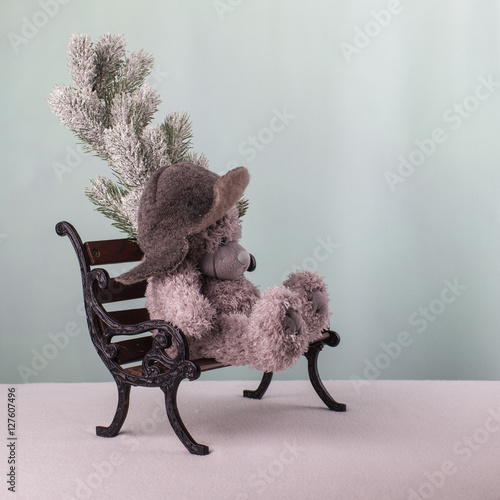 Принти на полотні Teddy bear with a winter cap sitting tedious on the bench and wa