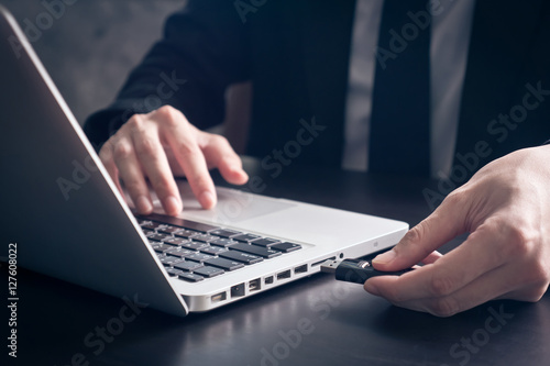 Close up of Businessman using flash drive connect to laptop on the desk. photo
