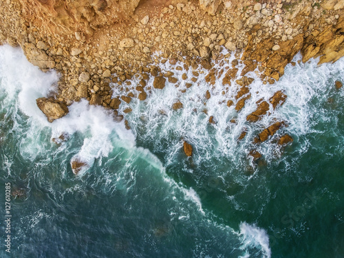 Aerial. Waves swim to the rocky shore. photo