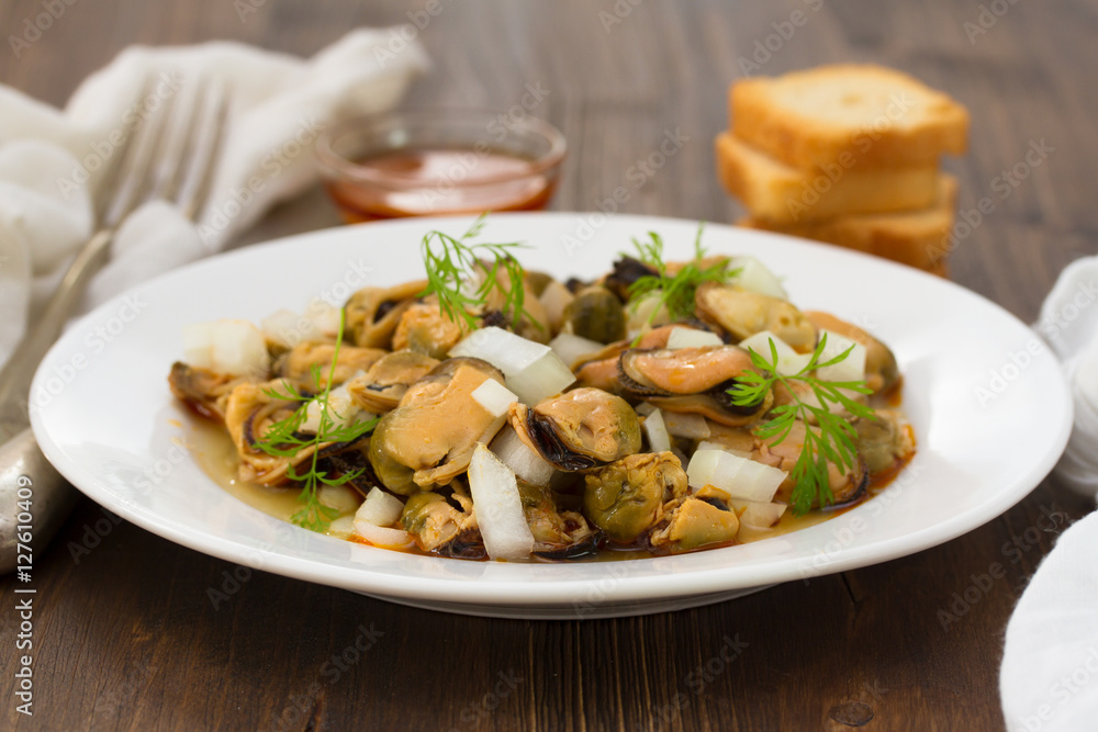salad mussels with onion in sauce in white plate on wooden backg