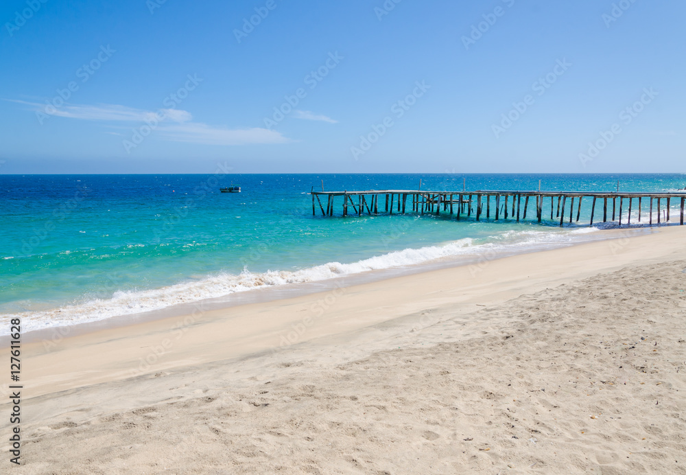 Long simple wooden jetty leading into turquoise blue ocean in Angola