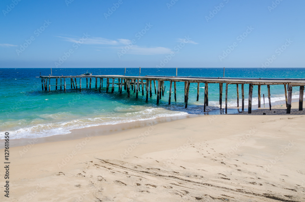 Long simple wooden jetty leading into turquoise blue ocean in Angola