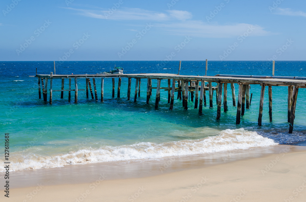 Long simple wooden jetty leading into turquoise blue ocean in Angola Long simple wooden jetty leading into turquoise blue ocean in Angola
