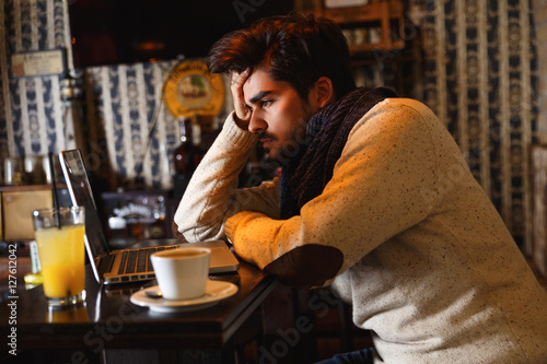 Young man sitting in a cafe and working on his laptop.