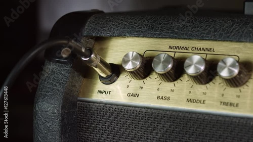 Plugging in cable jack guitar amplifier and turn up gain level