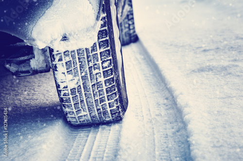 Closeup of car tires in winter on the road covered with snow © candy1812