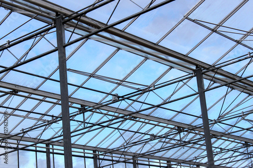 Glazing transparent roof of a contemporary greenhouse building under blue sky.