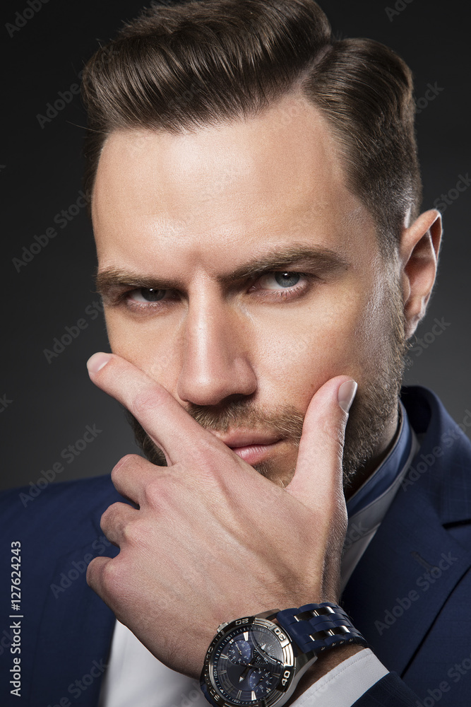 Young bearded man looking at camera. Wearing suit and watch Young bearded man looking at camera. Wearing suit and watch